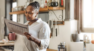 Smiling African American woman reading the newspaper in the morning